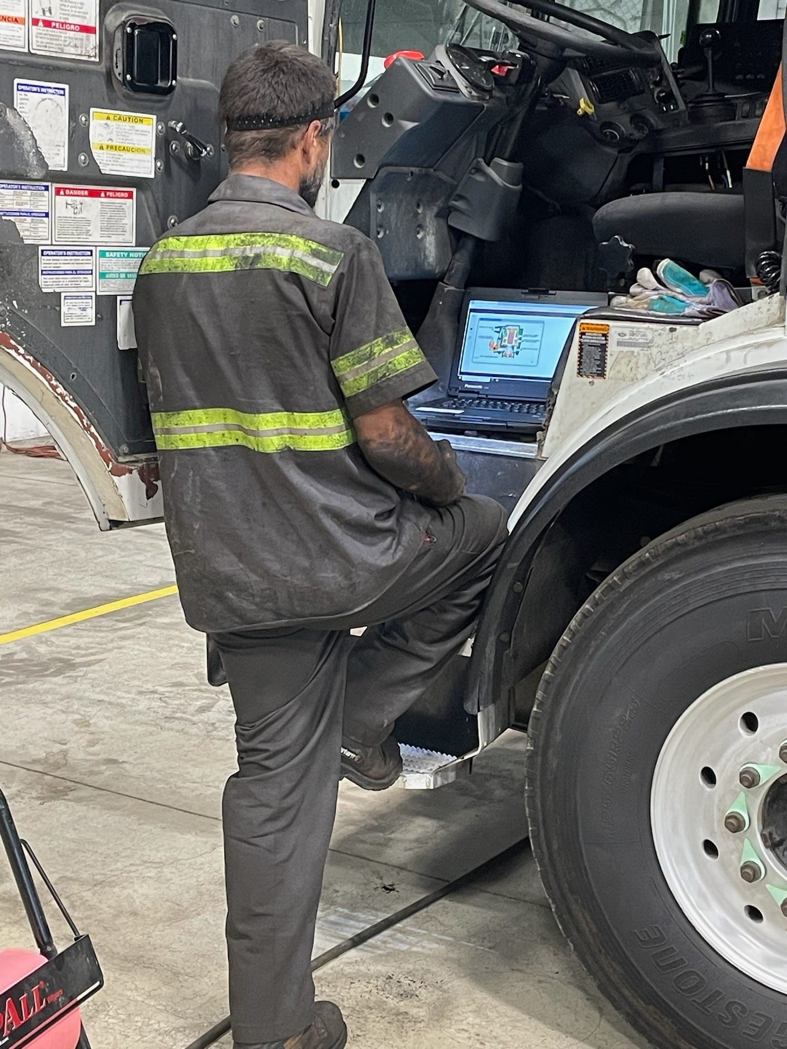 A man is sitting on the side of a truck in a garage.