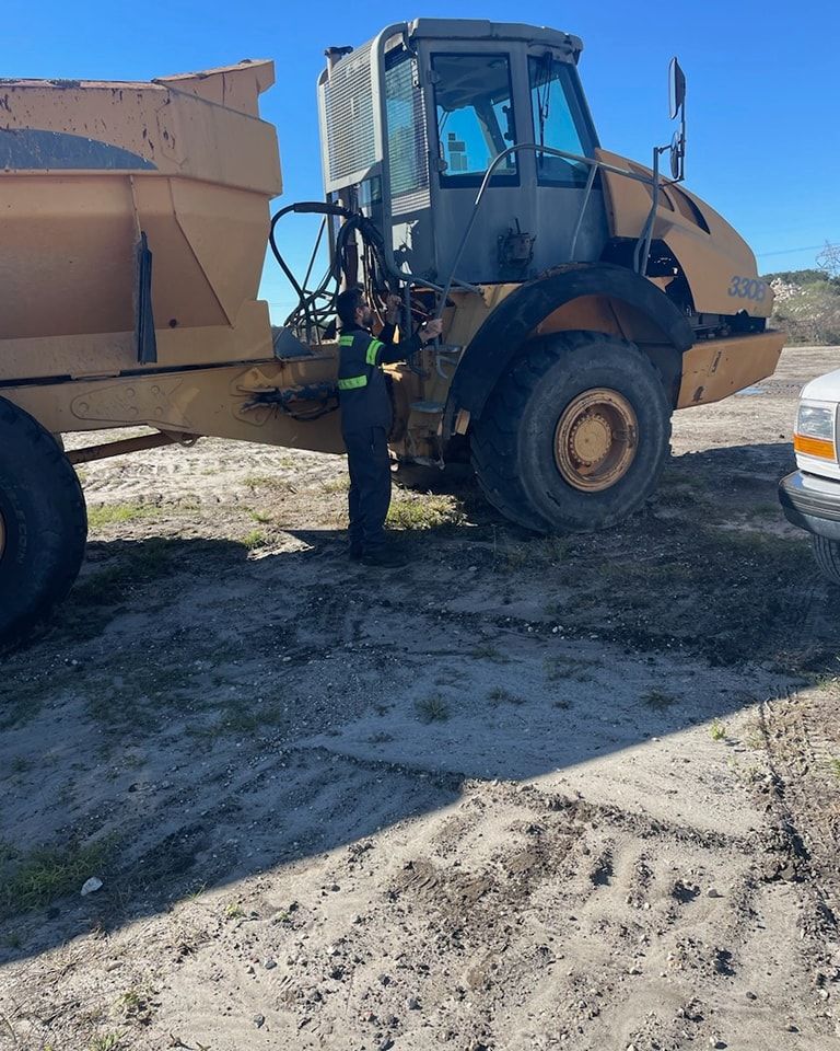 A man in a safety vest is standing next to a dump truck