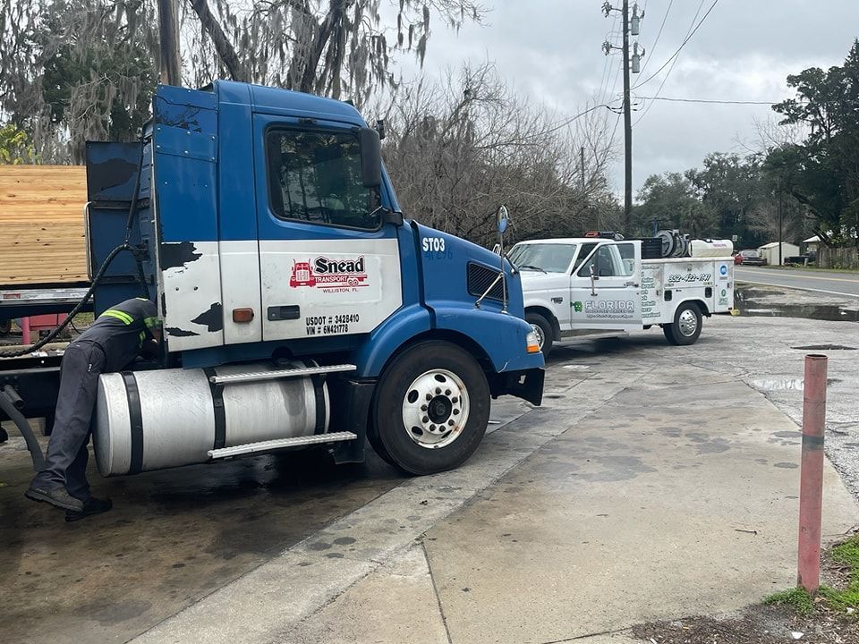 A blue semi truck is parked on the side of the road next to a white truck.