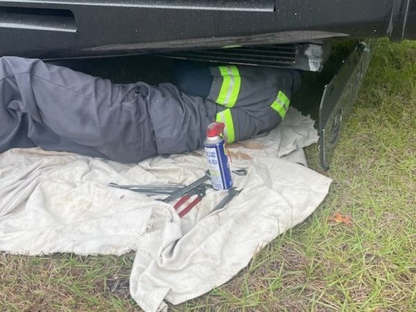 A man is laying under a car with tools.