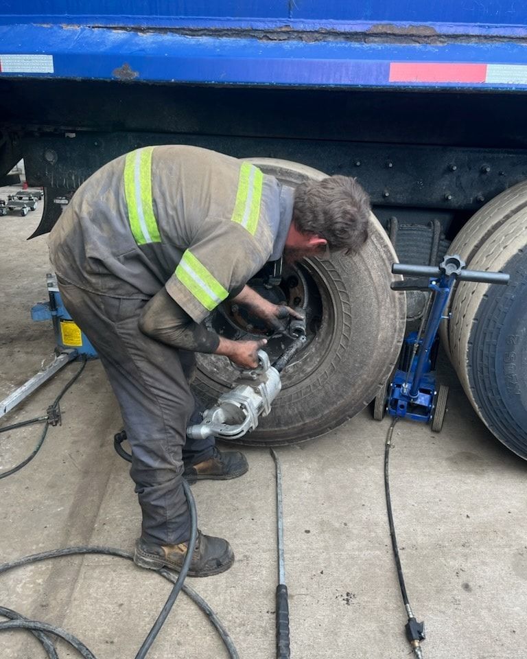 A man is working on a tire on a truck.