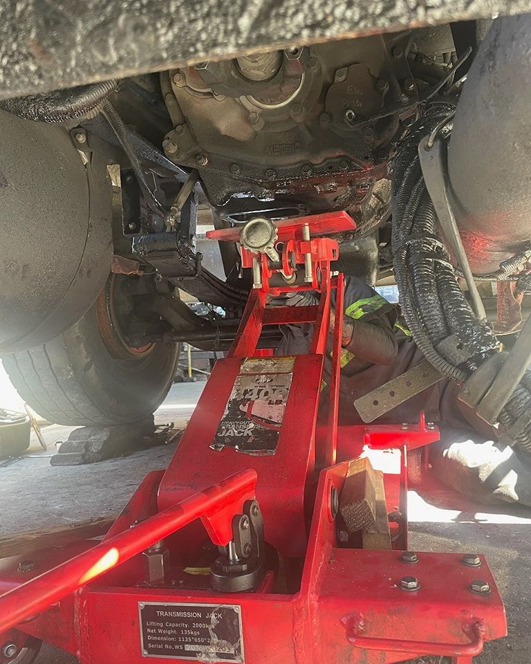 A red jack is sitting underneath a car.
