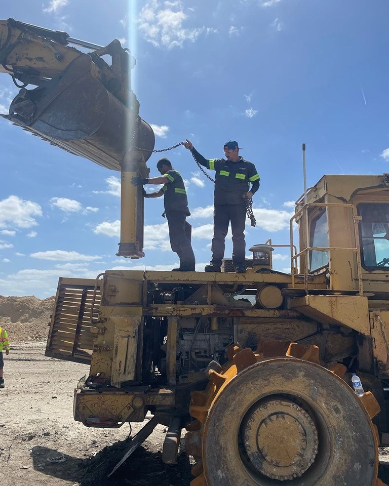 Two men are working on a large construction vehicle