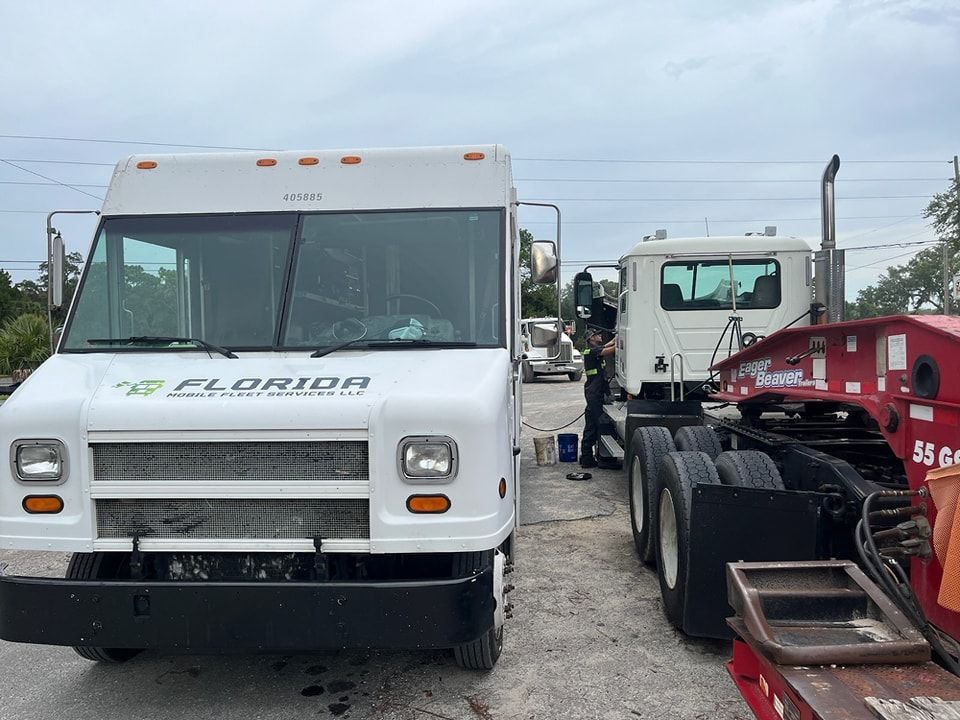 A white truck is parked next to a red trailer in a parking lot.