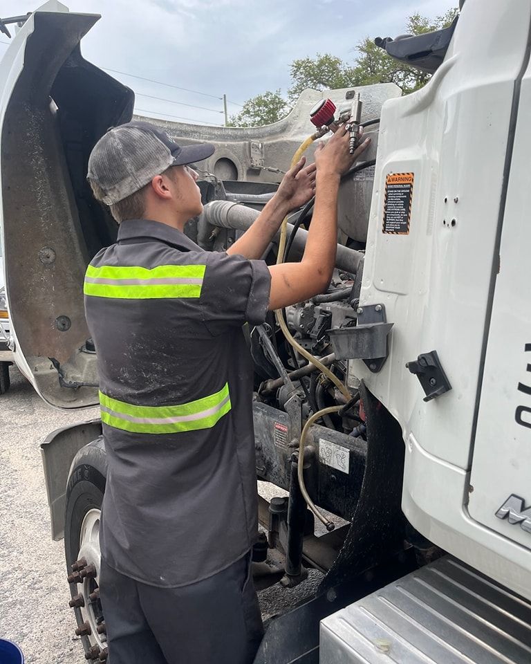 A man is working on the engine of a truck.