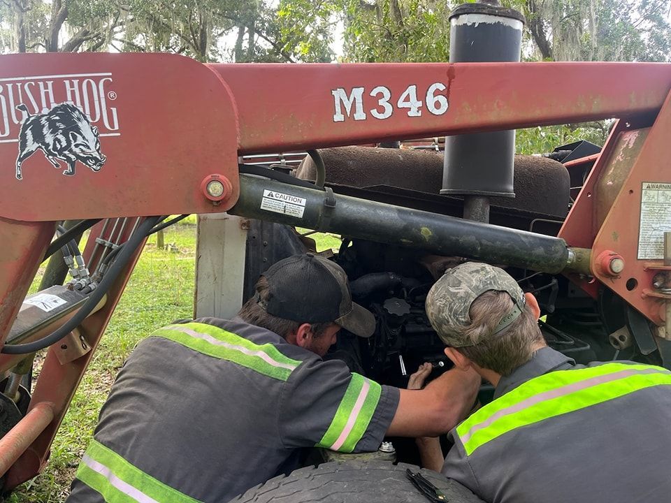 A group of men are working on a tractor.