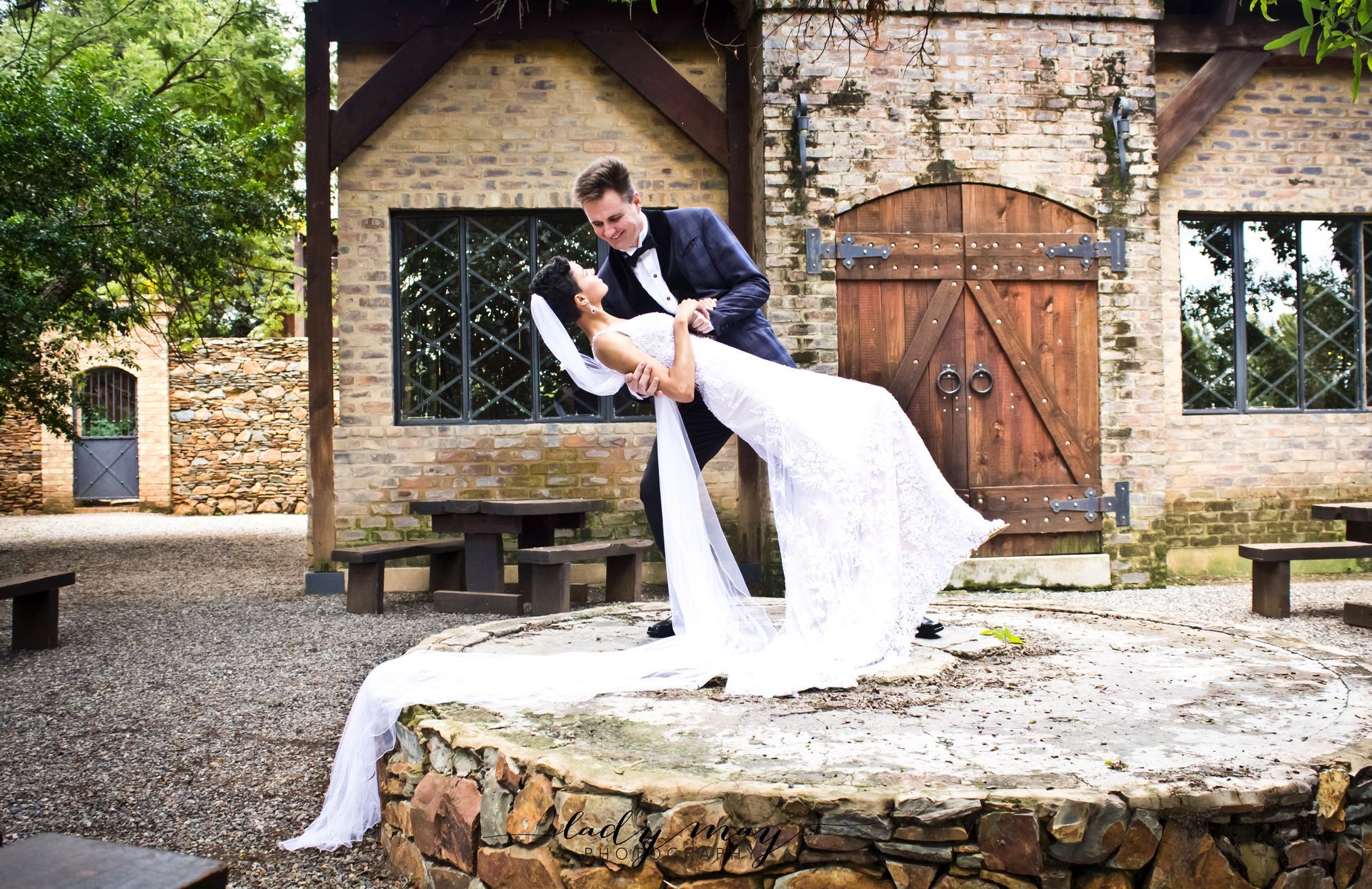A bride and groom are posing for a picture in front of the Riverside Castle building.