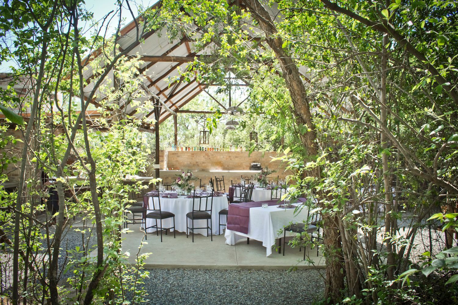 A table and chairs under a canopy in the woods.