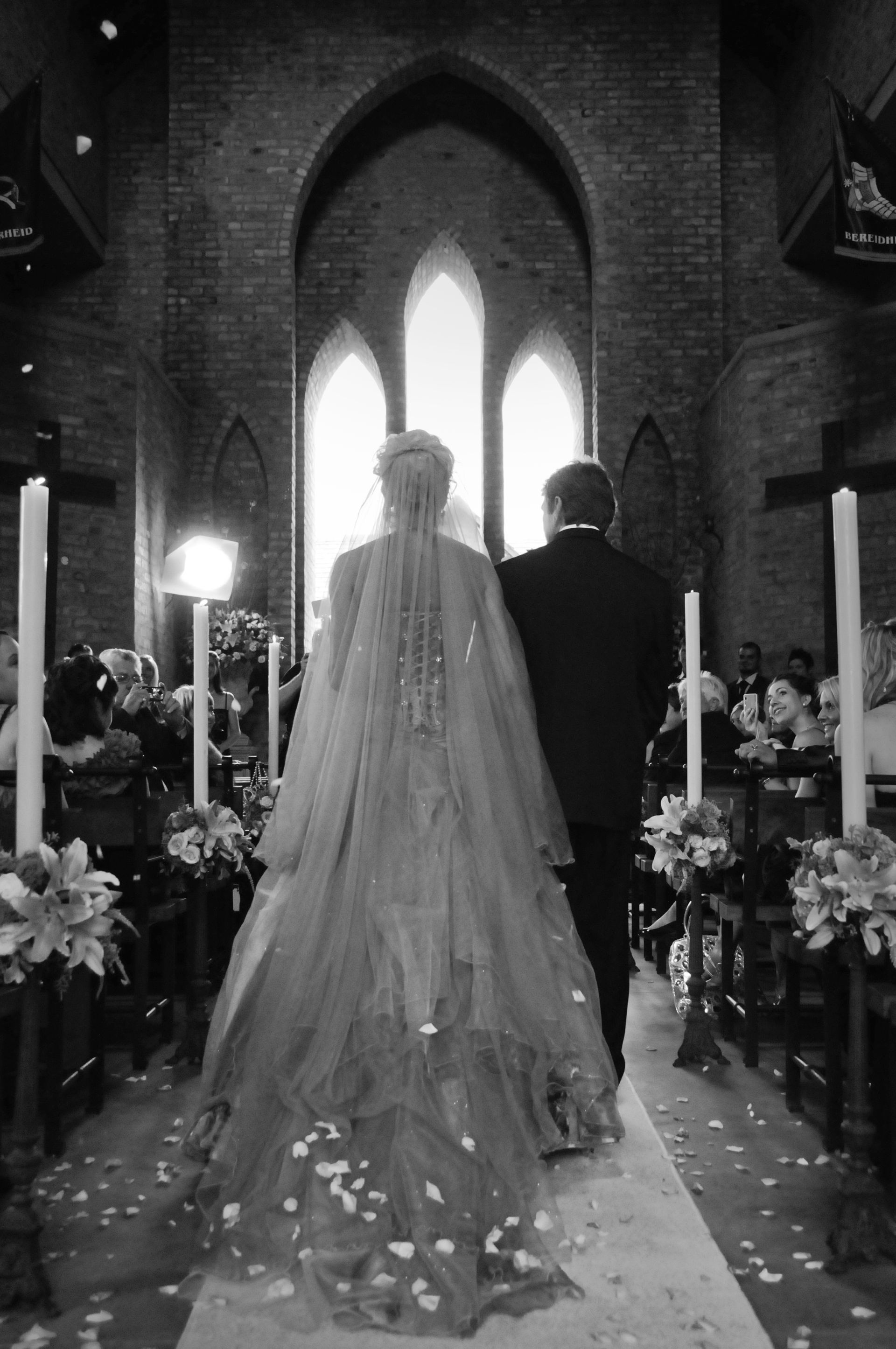 A bride and groom are walking down the aisle of the chapel at Riverside Castle.