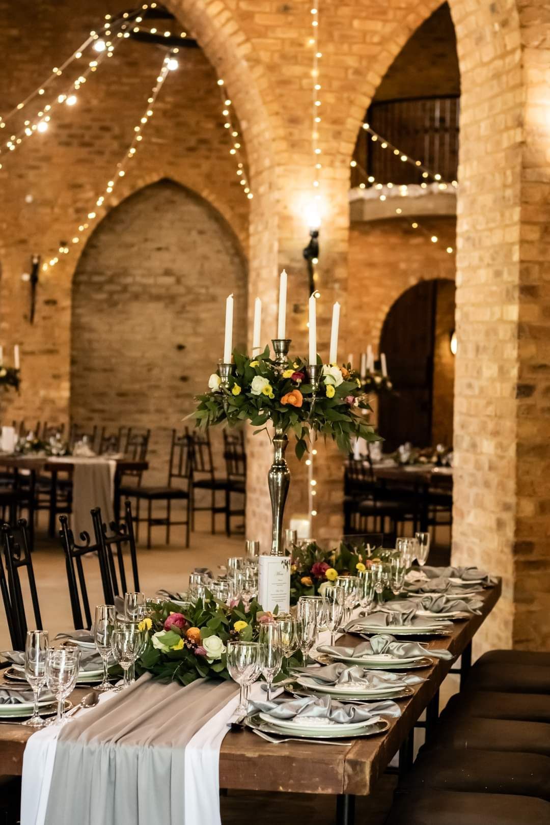 A long table with plates , candles , and flowers on it in the main Reception Hall at Riverside Castle in Pretoria East.