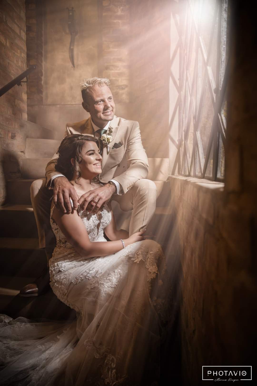 A bride and groom are sitting on stairs at Riverside Castle in Pretoria East.