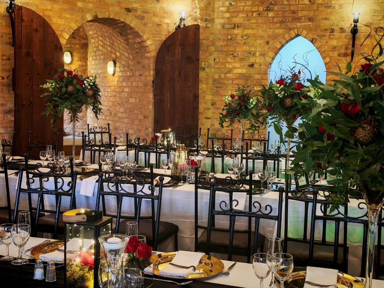 Elegant banquet table in a stone-vaulted hall, set with black-and-white linens and floral centerpieces