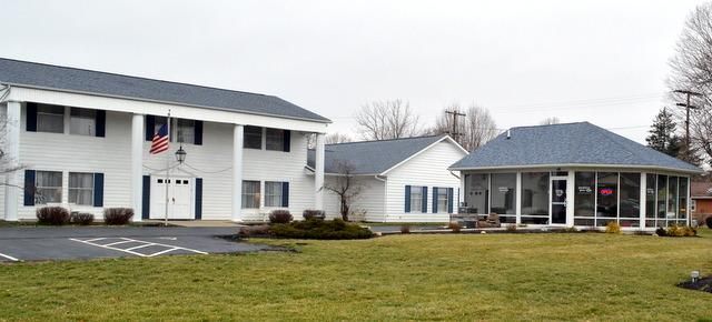 White building and small gazebo on a lawn under an overcast sky