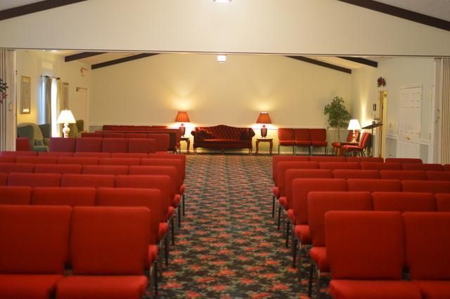 Empty church sanctuary with red pews facing a small stage and altar area