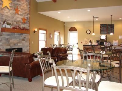 Cozy open-plan living room and dining area with leather chairs, metal table, and stone fireplace