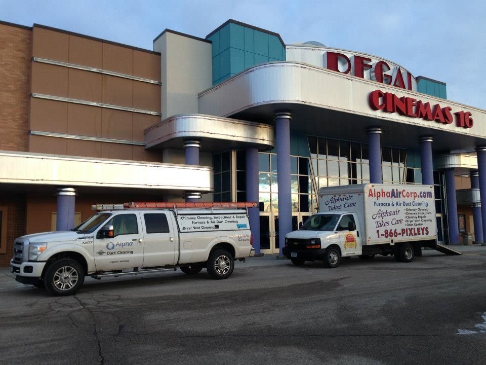 Two service trucks parked outside a movie theater: DFG Cinemas 16.