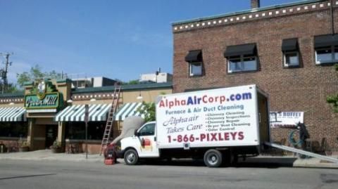 Alpha Air Corp. truck parked in front of a building with an awning, offering furnace and air duct cleaning services.