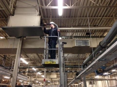 A person on a scissor lift working on a large metal structure in a factory.