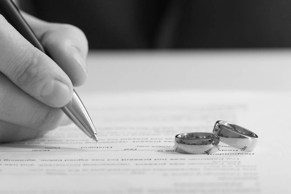 Hand Signing Document With Wedding Rings — Paradise Law In Sandgate, QLD