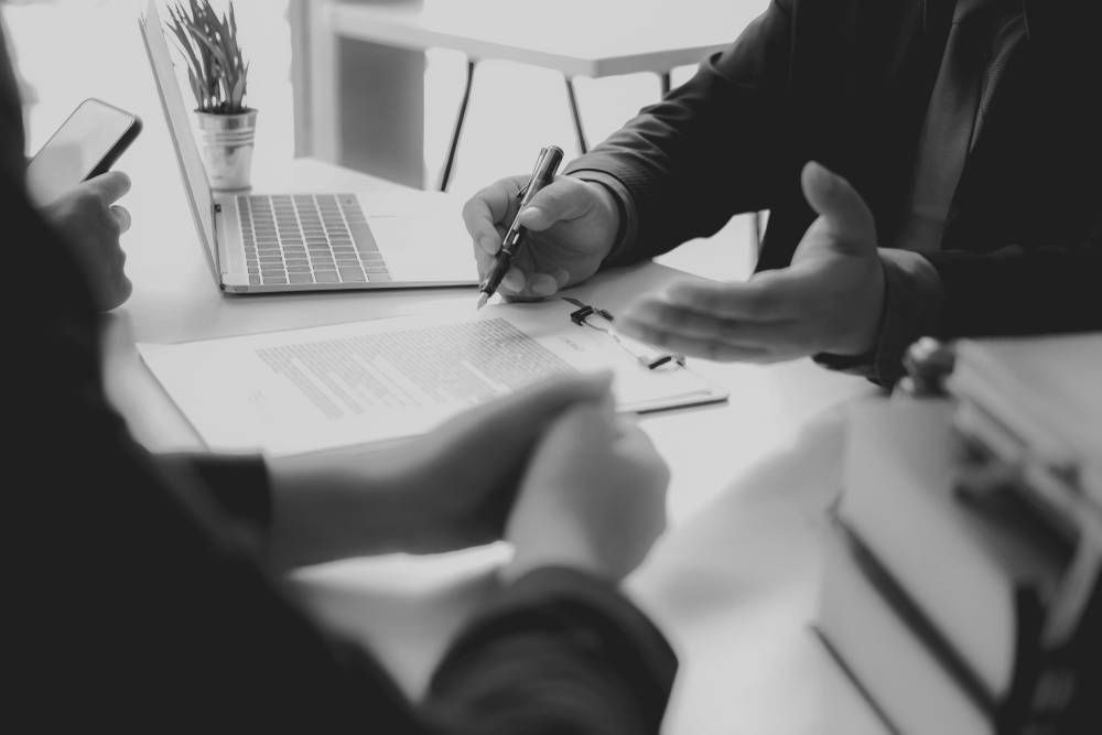 People Reviewing and Signing a Document at a Desk — Paradise Law In Sandgate, QLD