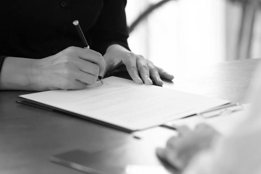Person Signing a Document on a Table. Hands Hold Pen, Focused on the Paper — Paradise Law In Surfers Paradise, QLD