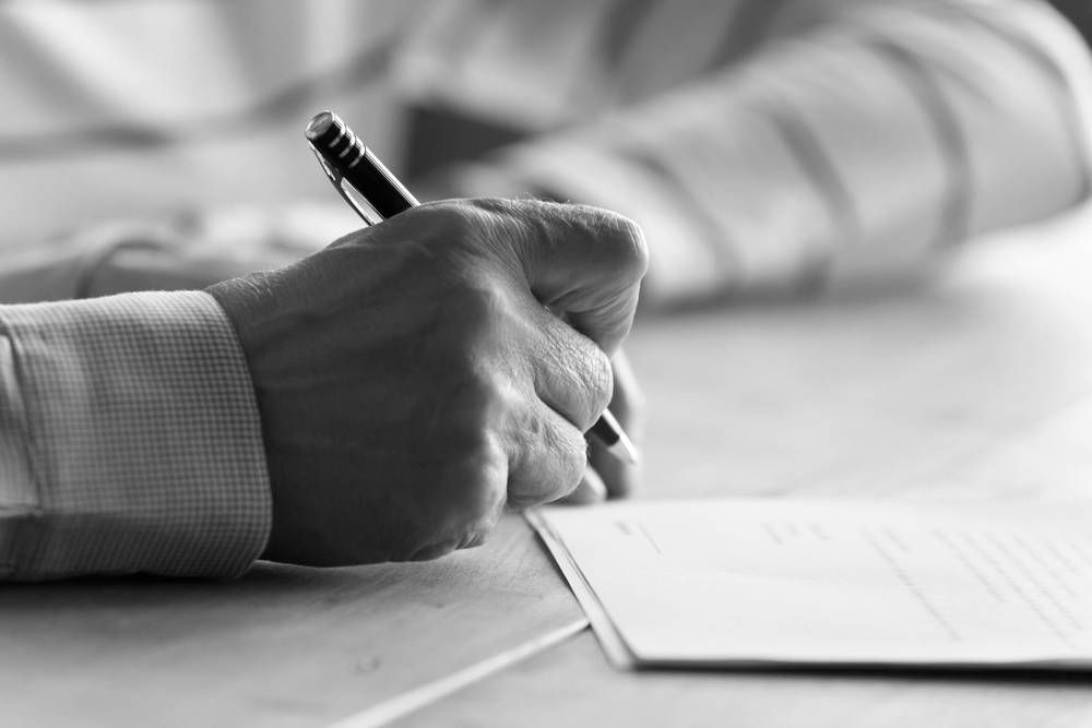 A Hand Holding a Pen, Writing on a Document — Paradise Law In Tweed Heads, NSW