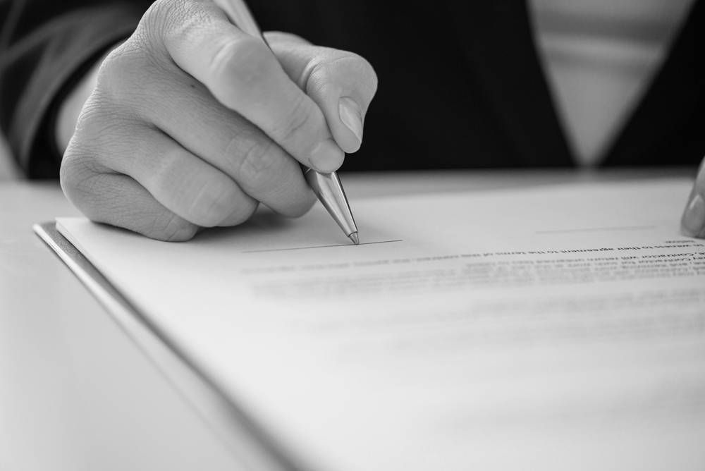 Hand Holding a Pen, Signing a Document — Paradise Law In Byron Bay, NSW