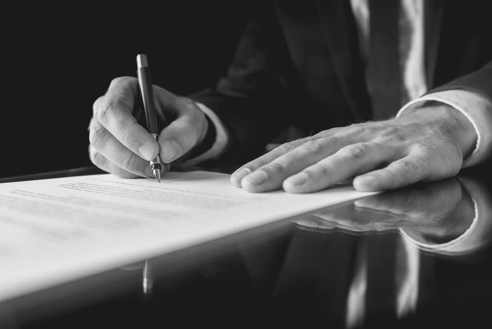 A Person's Hands Writing With a Pen on a Document — Paradise Law In Beaudesert, QLD