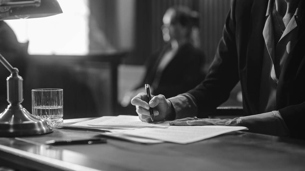 Person in Suit Writing at a Desk — Paradise Law In Brisbane, QLD