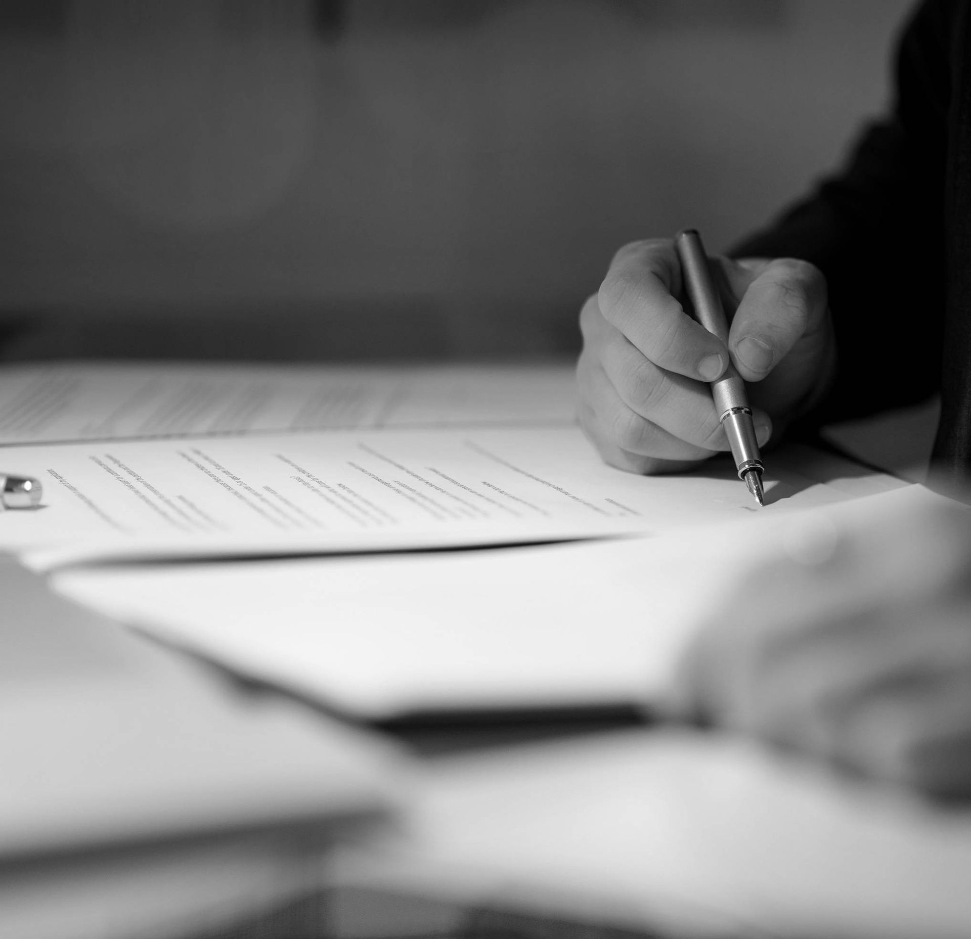 Person Signing a Document With a Pen at a Desk — Paradise Law In Maroochydore, QLD
