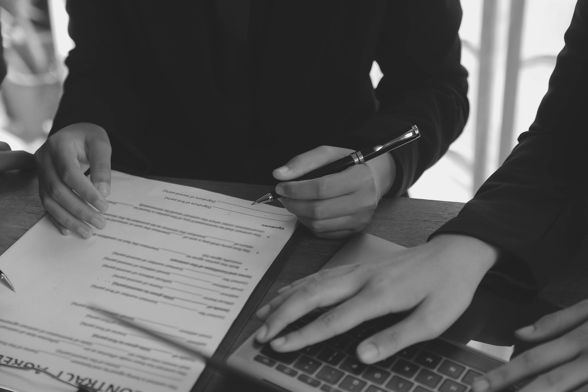 Hands Signing a Contract on a Table; Another Hand on a Laptop — Paradise Law In Ipswich, QLD