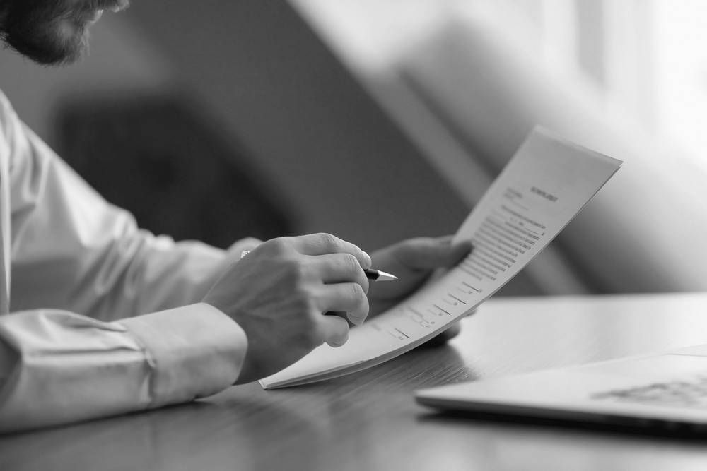 Person Holding a Pen, Reviewing a Document — Paradise Law In Caloundra, QLD
