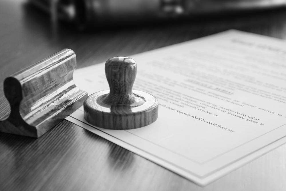 Wooden Stamp Next to a Document, on a Wooden Surface — Paradise Law In Southport, QLD