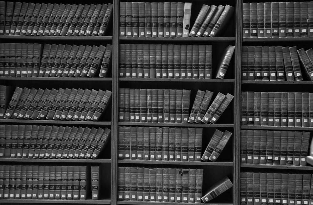Rows of Books Neatly Arranged on Wooden Bookshelves — Paradise Law In Gold Coast, QLD