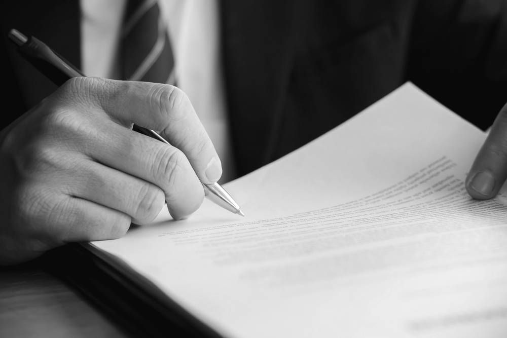 Person's Hand Signing a Document With a Pen — Paradise Law In Maroochydore, QLD