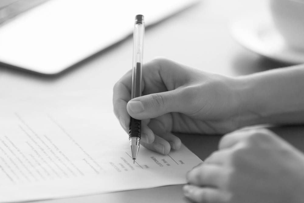 Hand Writing on a Document With a Pen — Paradise Law In Sandgate, QLD