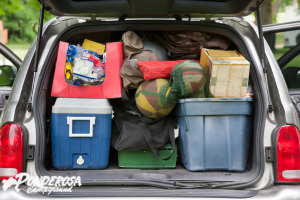Open SUV trunk packed with camping gear, coolers, bags, and boxes