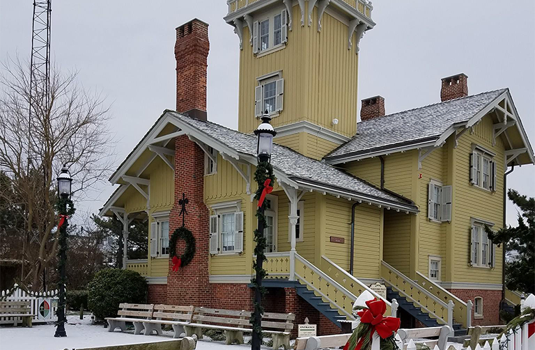A yellow house with a brick chimney is decorated for christmas