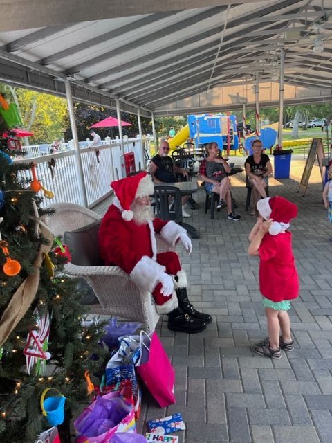 A little girl in a red shirt is talking to santa claus