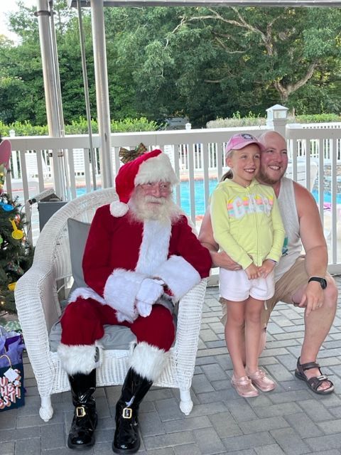 A man and a little girl are posing for a picture with santa claus
