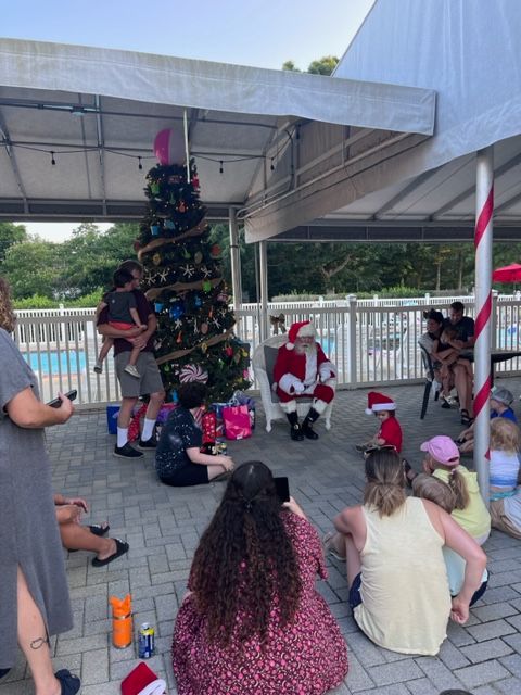 A group of people sitting around a christmas tree with santa claus