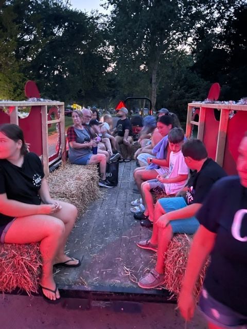 A group of people are sitting on hay bales in a wagon
