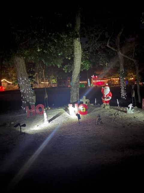 A christmas decoration in a yard at night with a santa claus statue.