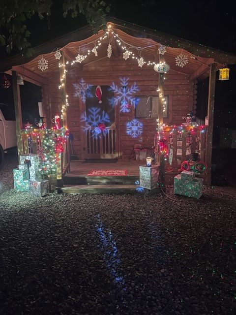 A wooden cabin decorated for christmas with christmas lights and presents.