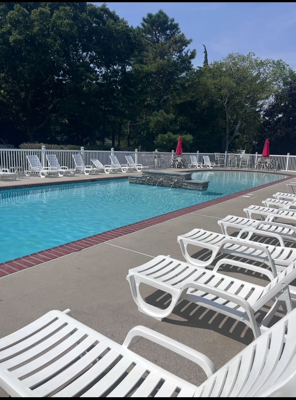 Outdoor swimming pool with white lounge chairs and red umbrellas on a sunny day