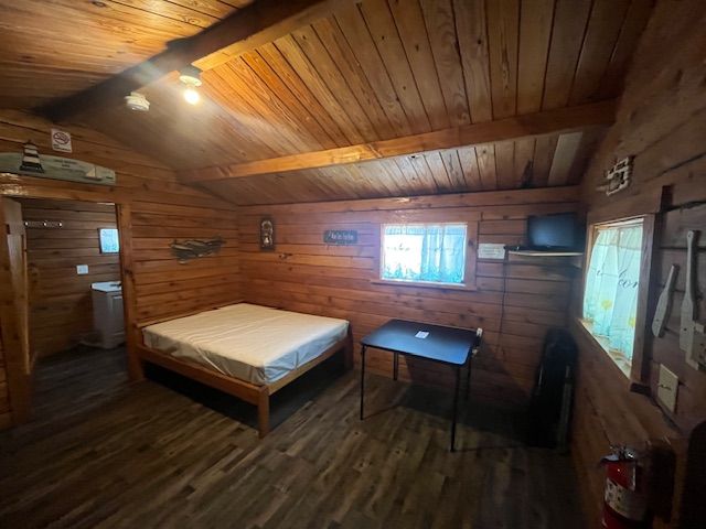Rustic wooden cabin bedroom with a bed, desk, windows, and slanted ceiling with lights