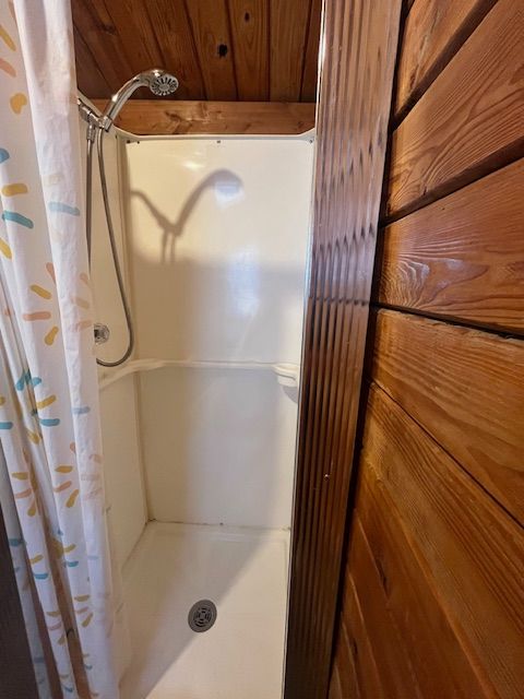 Wood-paneled cabin bedroom with a small bathroom visible through an open doorway.