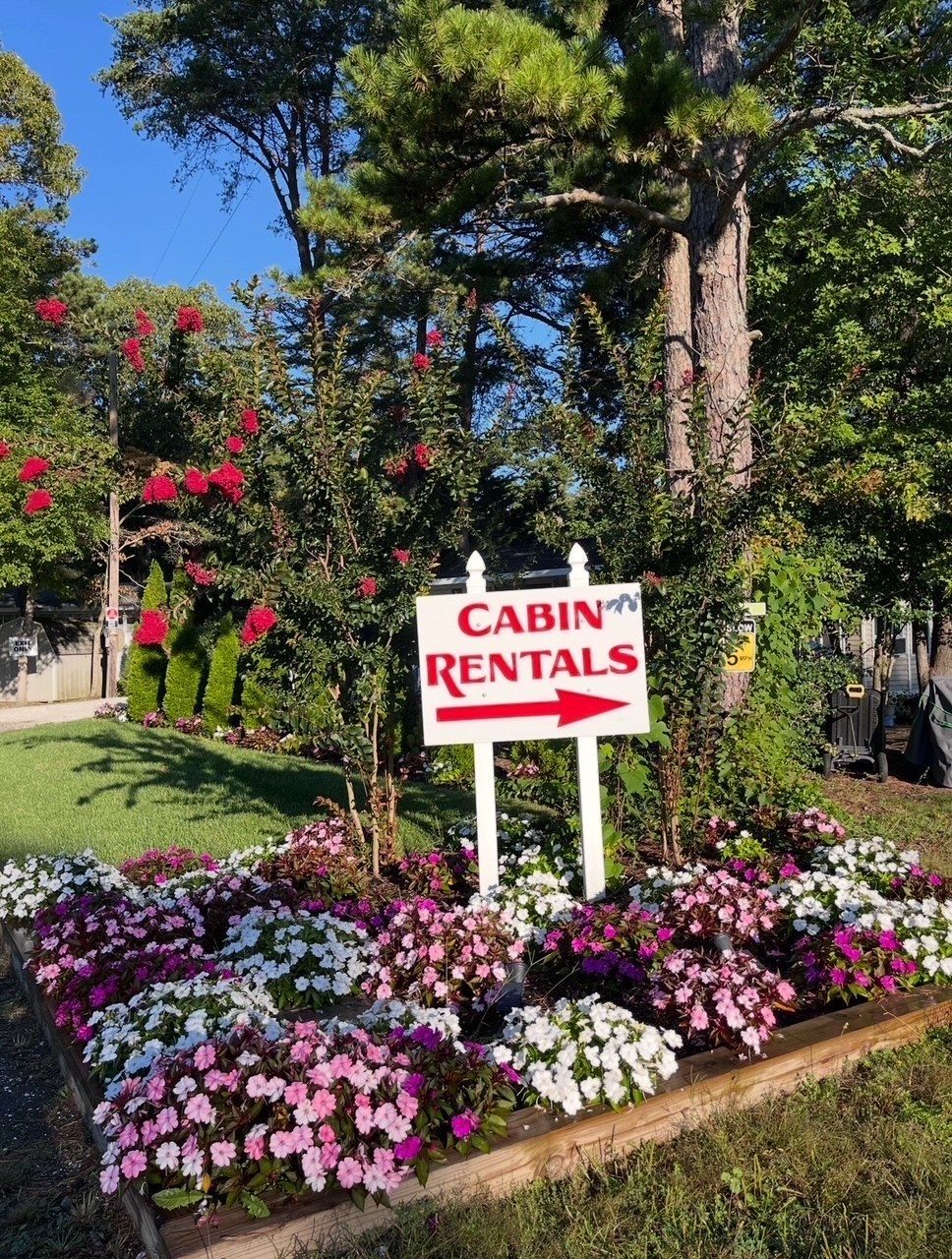 Cabin rentals sign amid colorful flowers and trees in a landscaped garden