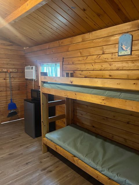 Wooden bunk bed in a cozy cabin-style room with wood-paneled walls and a slanted ceiling