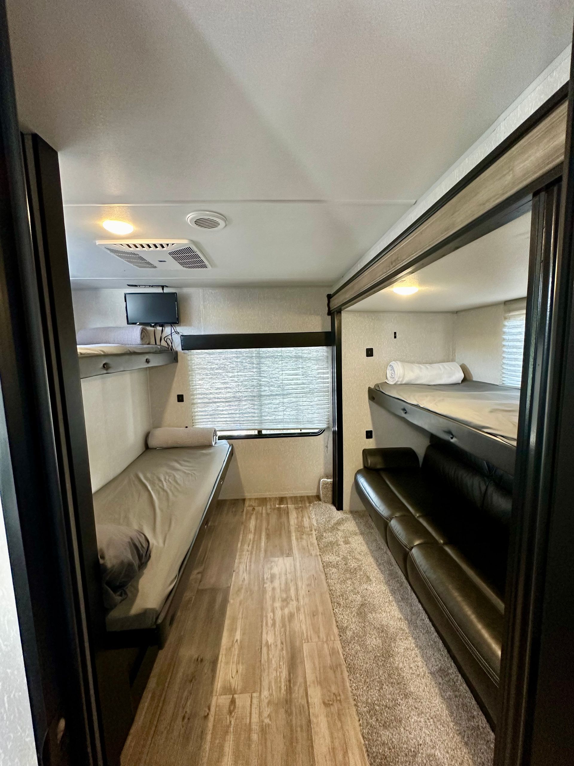 A rv with bunk beds and a couch in the back.